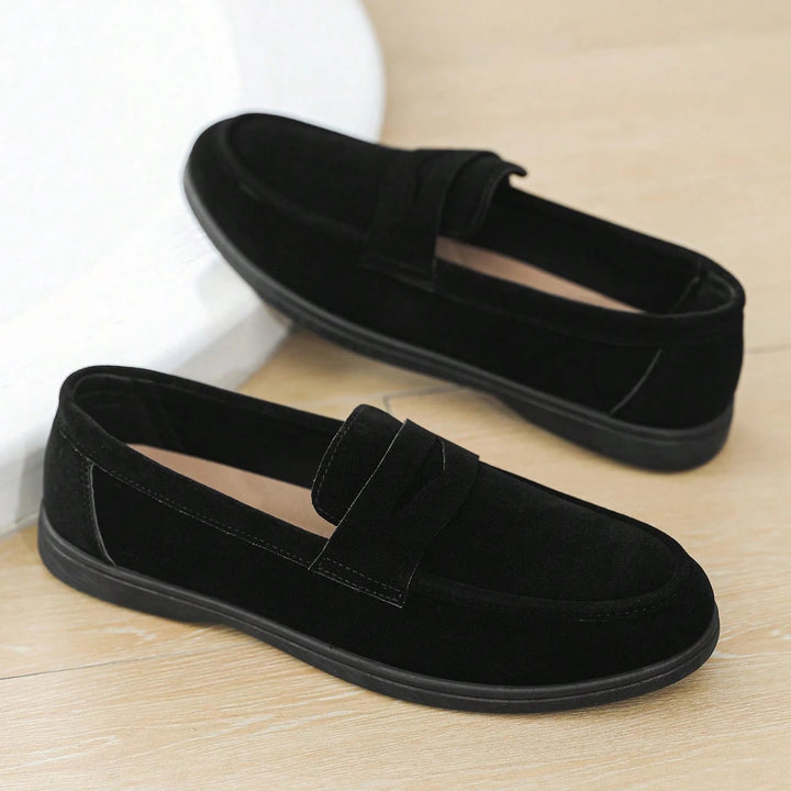 Pair of black loafers on a wooden floor