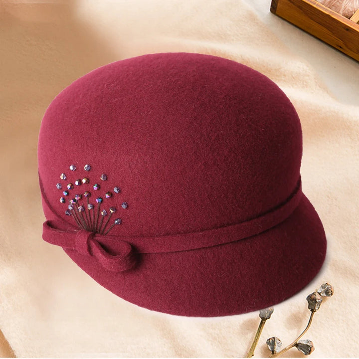 Maroon hat with decorative elements on a beige surface