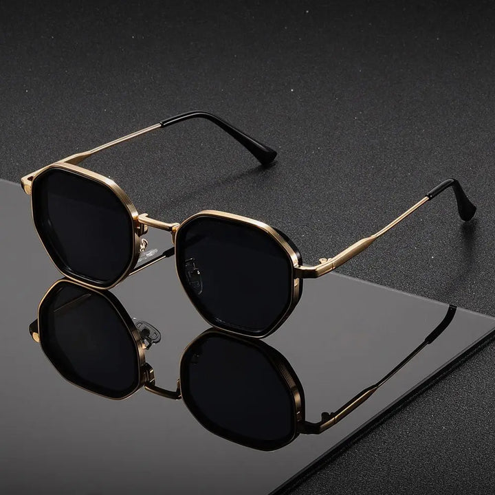 Gold-framed sunglasses with black lenses on a reflective black surface