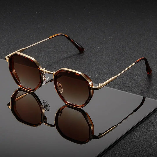 Sunglasses with gold frame and brown lenses on a reflective black surface