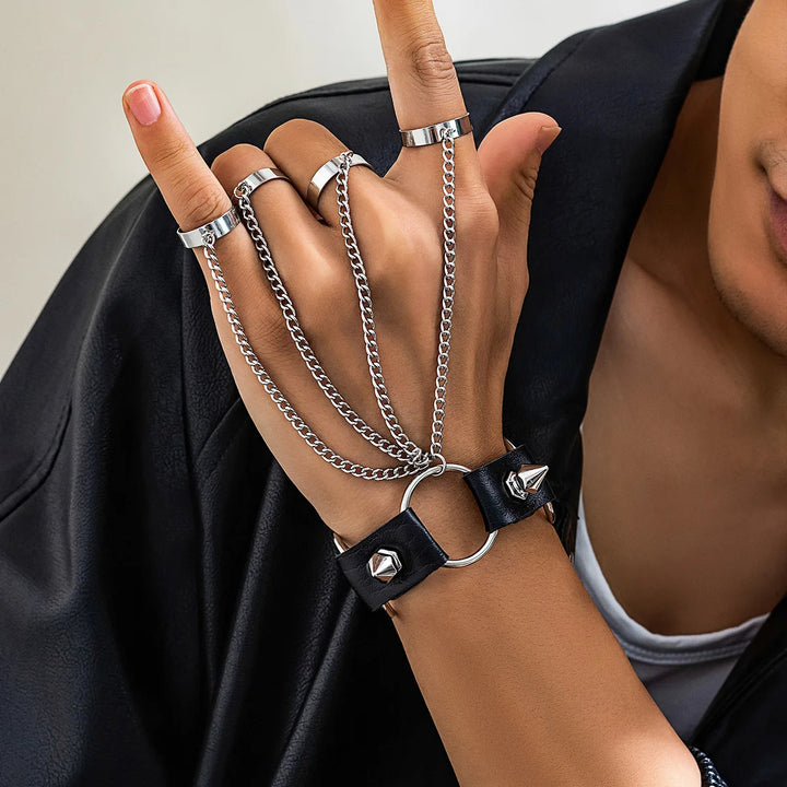 Hand wearing multiple silver rings and a black leather bracelet with metal clasp.