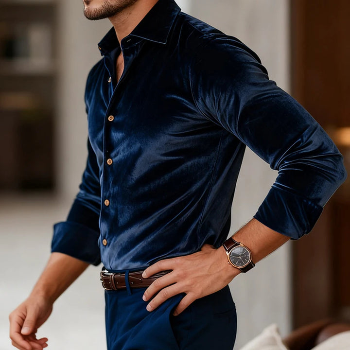Man wearing a dark blue velvet shirt with a blurred indoor background