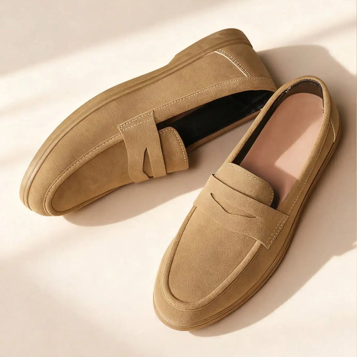 Pair of tan loafers on a light beige background