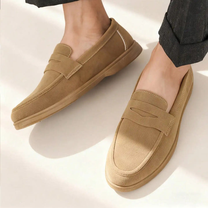Tan loafers worn by a person on a light background