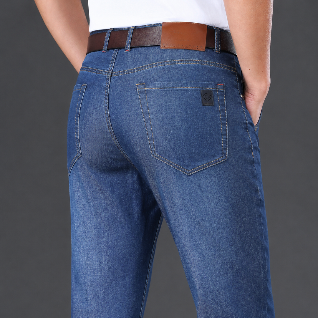 Person wearing blue jeans with a brown belt on a gray background