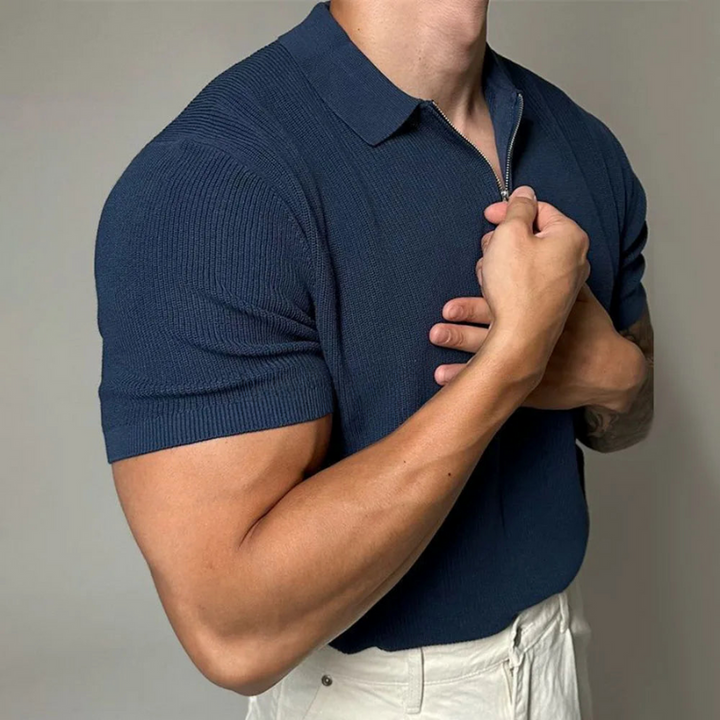 Man wearing a navy blue polo shirt against a plain background