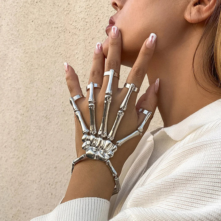 Silver skeleton hand bracelet on a person's wrist with a neutral background