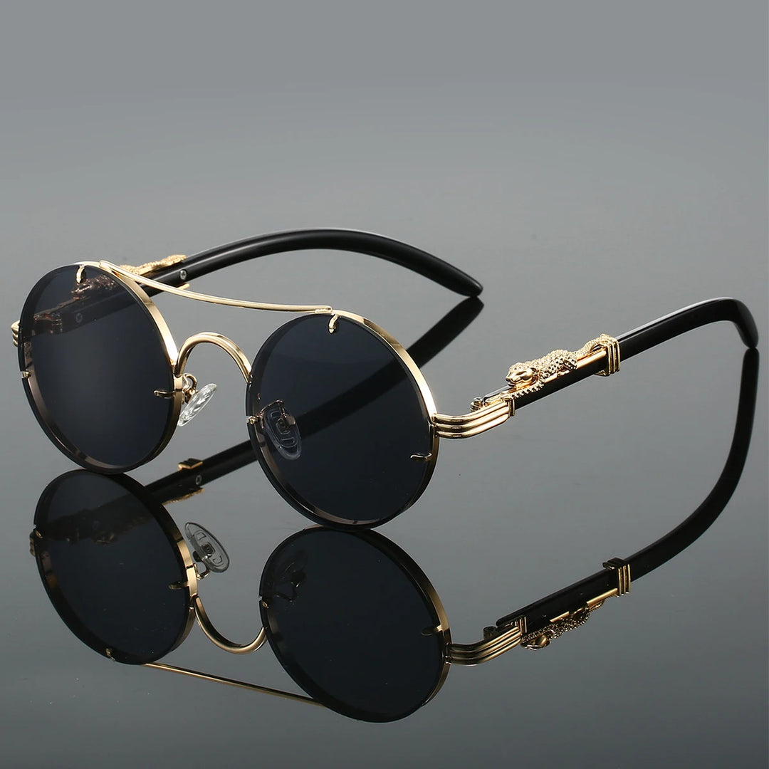 A pair of round-shaped, vintage style sunglasses with a double bridge design and intricately detailed temples. The lenses are tinted blue, and the overall color scheme includes gold and red.