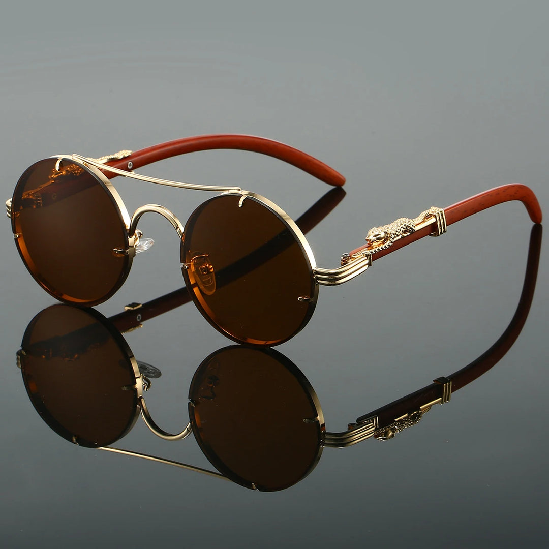 A pair of round-shaped, vintage style sunglasses with a double bridge design and intricately detailed temples. The lenses are tinted blue, and the overall color scheme includes gold and red.