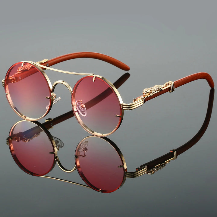 A pair of round-shaped, vintage style sunglasses with a double bridge design and intricately detailed temples. The lenses are tinted blue, and the overall color scheme includes gold and red.