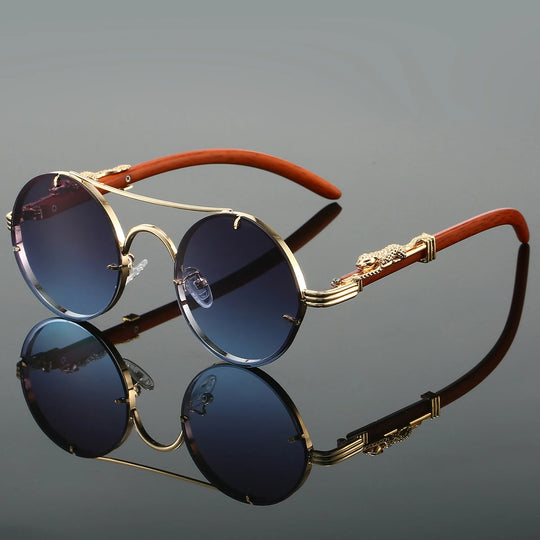 A pair of round-shaped, vintage style sunglasses with a double bridge design and intricately detailed temples. The lenses are tinted blue, and the metal frame appears to be gold-colored.