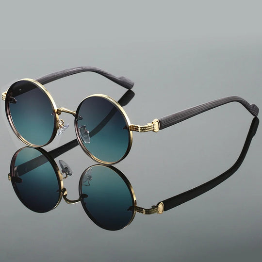 A pair of oval-shaped sunglasses with gradient blue-to-yellow lenses and gold-colored metal rims.