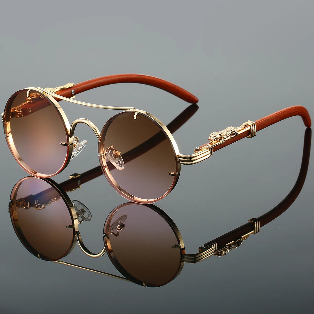 A pair of round-shaped, vintage style sunglasses with a double bridge design and intricately detailed temples. The lenses are tinted blue, and the overall color scheme includes gold and red.