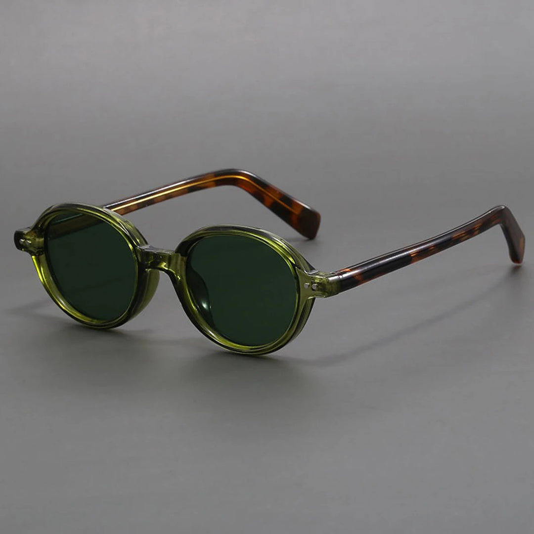 A pair of oval-shaped sunglasses with green tinted lenses and a patterned frame, displayed against a gray background.