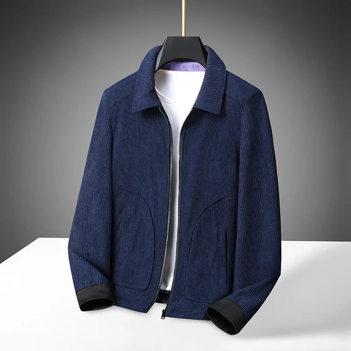 A navy blue corduroy coat jacket with a classic lapel, displayed on a white hanger against a dark background.