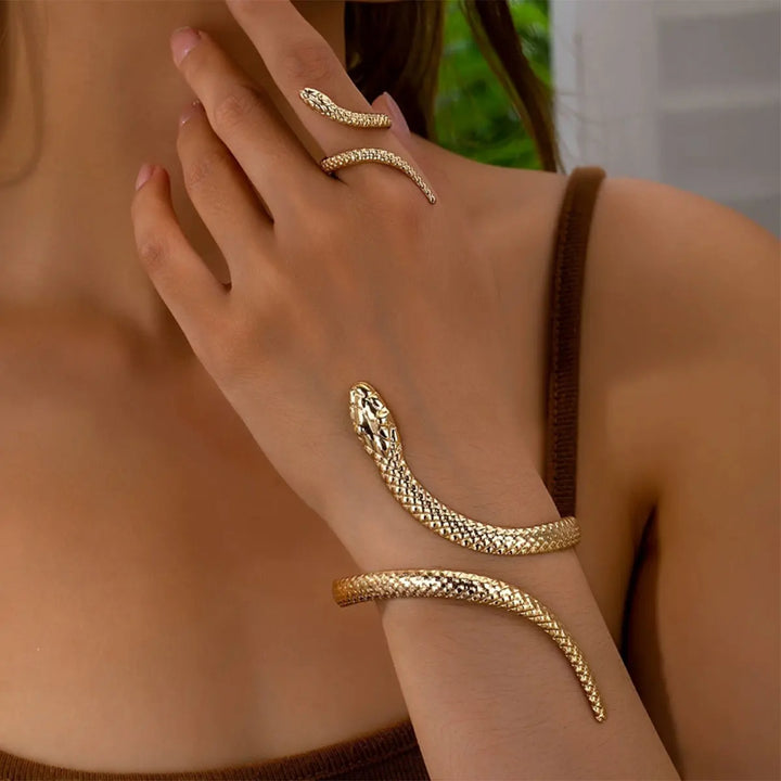 Gold snake-shaped bracelet on a wrist with a blurred background